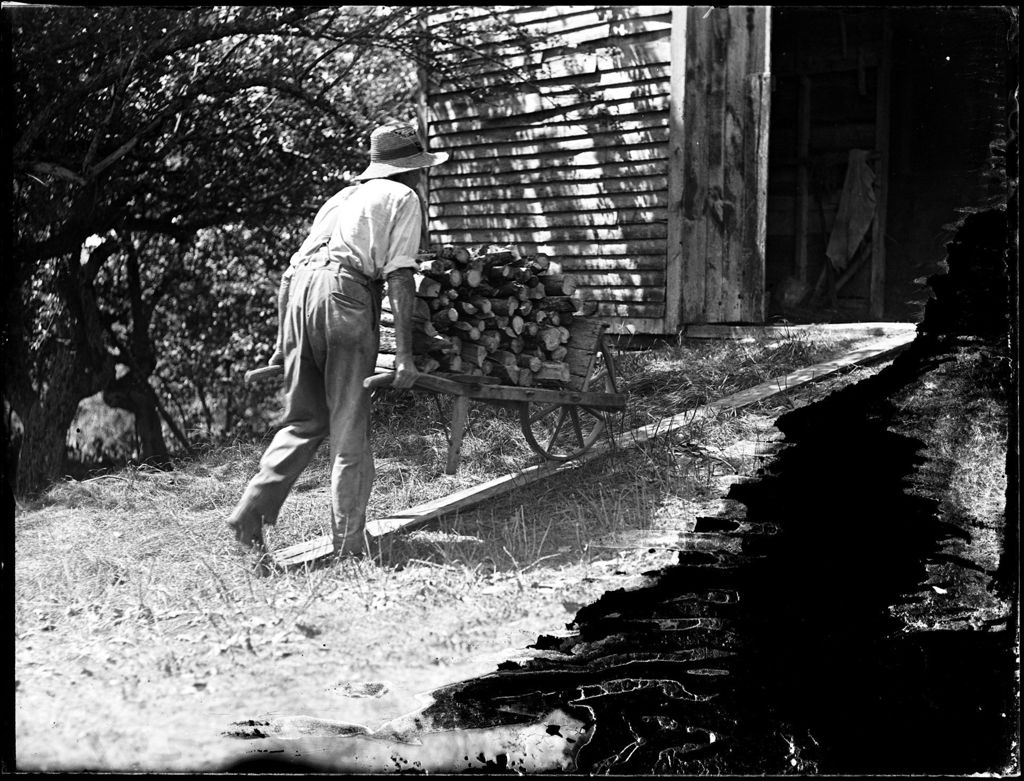 Miniature of Man Pushing A Wheelbarrow Full Of Firewood Into A Barn