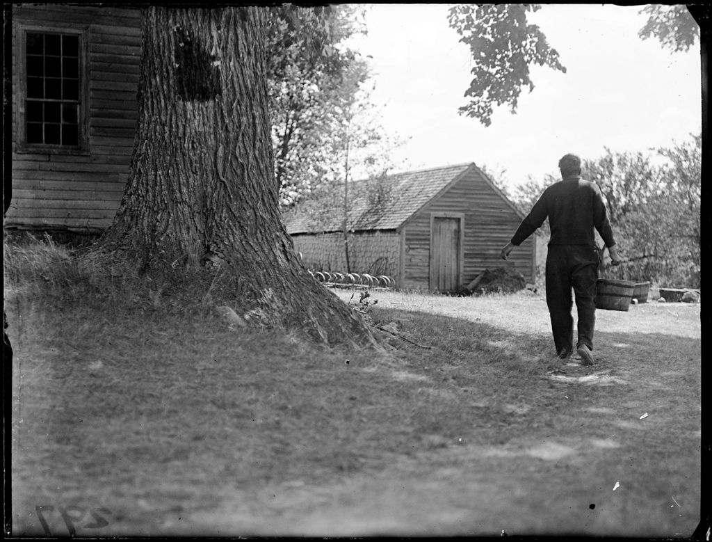 Miniature of Man Carrying A Bucket Of Water From A Well Outside A Rural Home