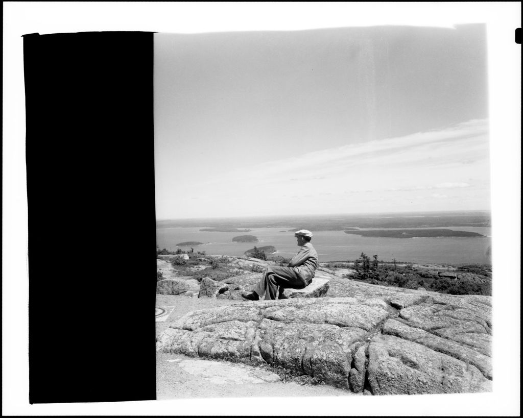 Miniature of Man Sitting On Rock On Cadillac Mountain In Acadia National Park, View Of Bay In Background