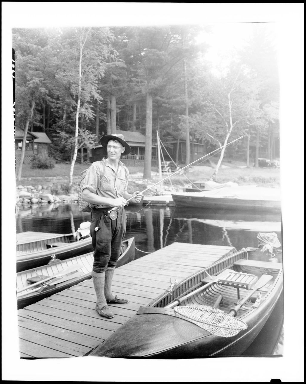 Miniature of Man With Fishing Rod Standing On Dock, Boats, Water And Cottages In Background