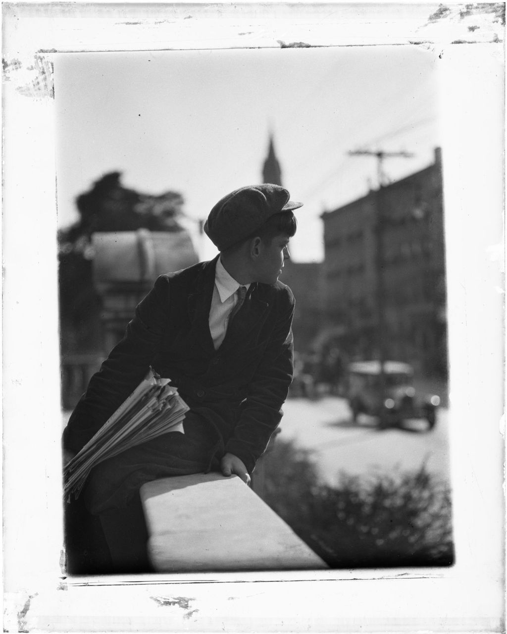 Miniature of Newsboy Looks Out Onto A City Street While Sitting On A Wall, Nj
