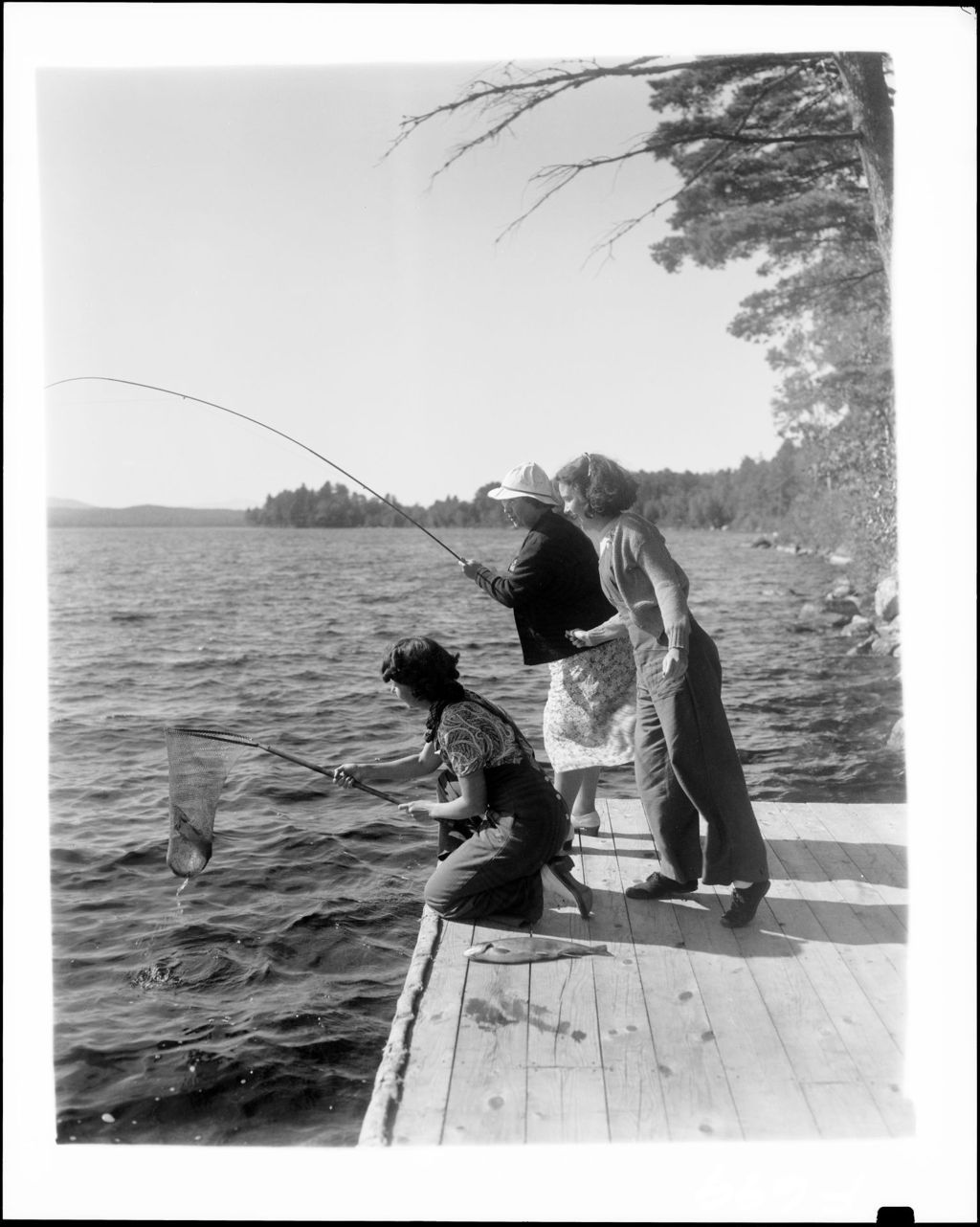 Miniature of Three Women Fishing From A Dock, One Netting Catch For The Other On Long Lake